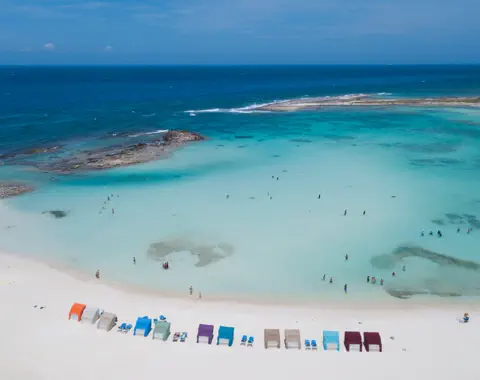 Aerial view of Aruba's turquoise water, beach cabanas, and shoreline.