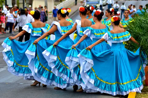 Dancers in blue dresses performing at an Aruba street celebration.